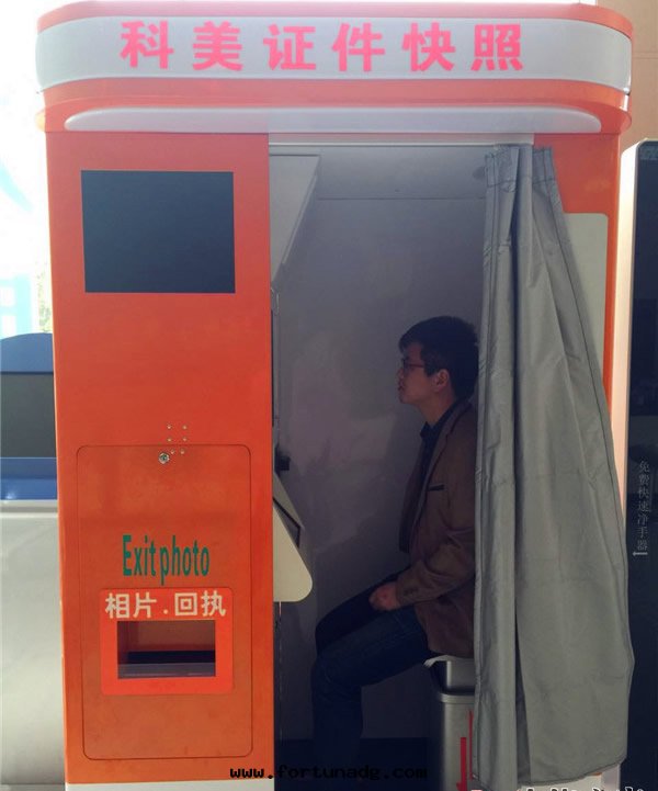 正(zhèng)在(zài)體(tǐ)验(yàn)自(zì)助拍照機(jī)使用(yòng)的(de)市(shì)民(mín)